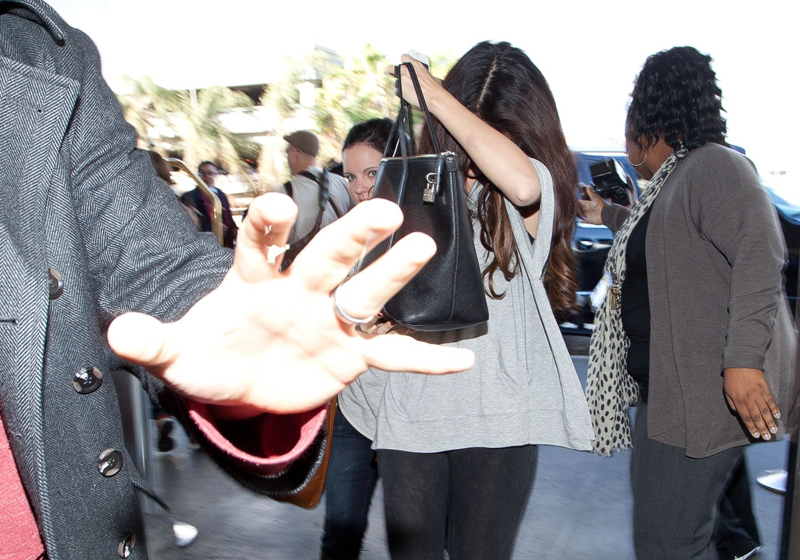 Selena se na letišti snažila schovat za obří kabelku.