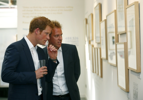Britský princ Harry si prohlíží výstavu fotografií o jeho charitativní činnosti.