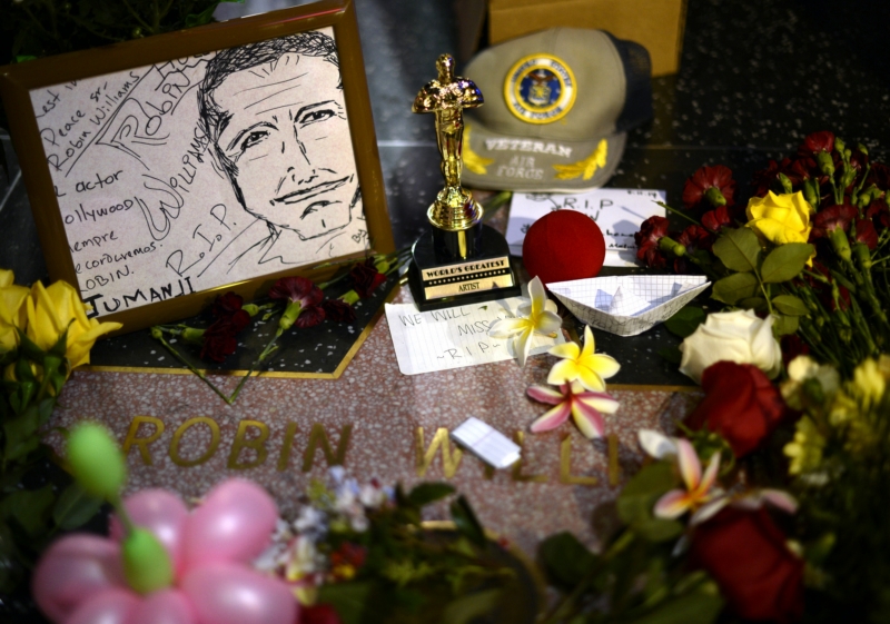 Fanoušci skládají květiny a drobné předměty k hvězdě Robina Williamse na hollywoodském chodníku slávy.