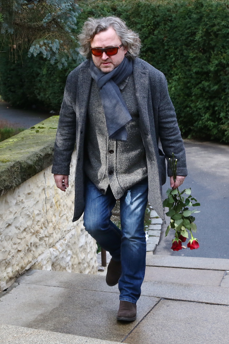 Jan Hřebejk kráčí do smuteční síně s třemi rudými růžemi.