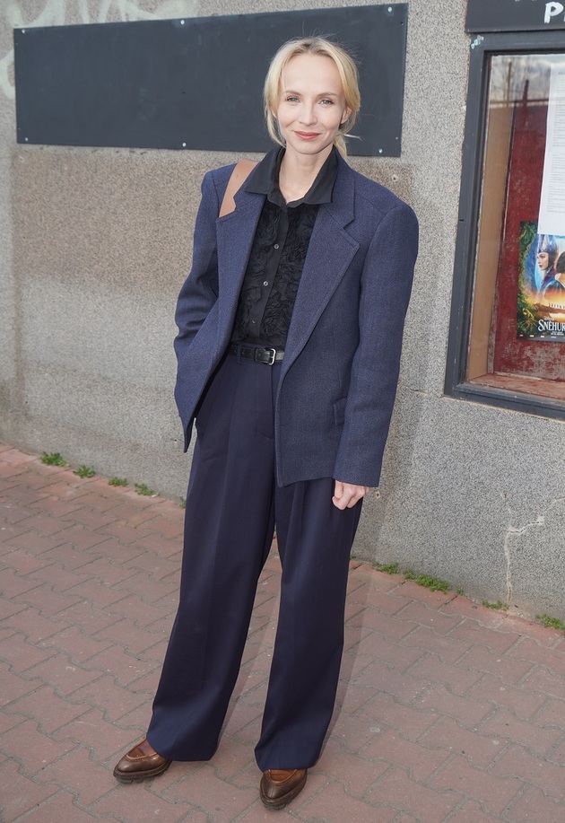 Jsem nadšená outfitem Jany Plodkové. Ryze pánský styl je osvěžen zdobenou dámskou halenkou. Líbí se mi kombinace materiálů a odstínů modré. Jediný drobný detail, který by mohl být lepší, je sladění pásku s botami.